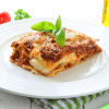 A scrumptious slice of Instant Pot lasagna with layers of pasta, rich meat sauce, and gooey melted cheese, served on a white plate. The dish is garnished with fresh basil leaves, adding a pop of green to the tempting, bubbling lasagna. A perfect representation of a classic Italian comfort food made effortlessly in the Instant Pot